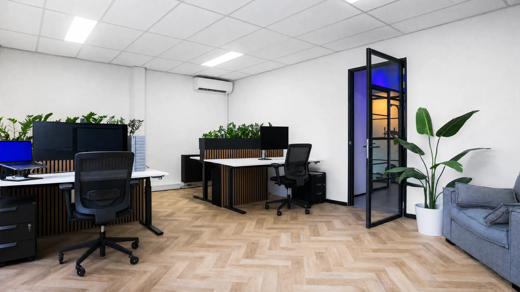 Lege zit-sta-bureaus met grote monitoren en zwarte bureaustoelen